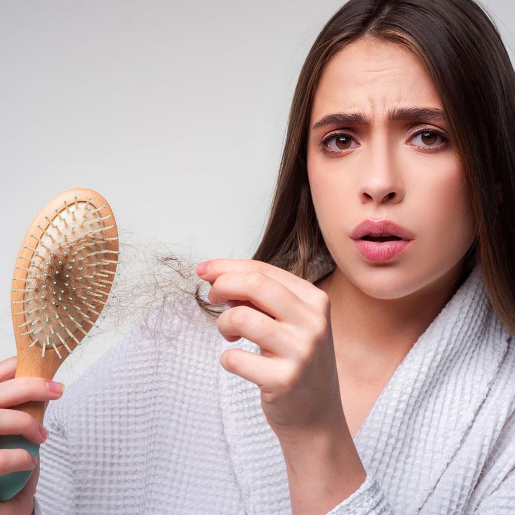 Woman looking at hair strands in her brush